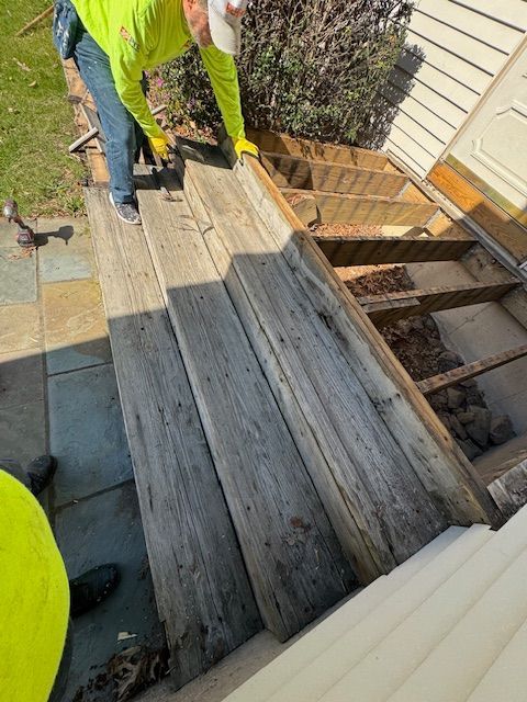Person removing wood from an outdoor staircase. The staircase is being renovated.