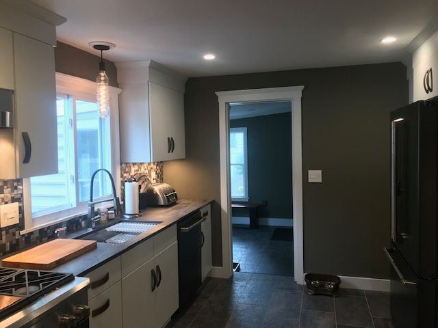 Kitchen with gray cabinets, black appliances, and dark green walls.
