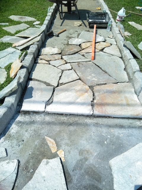 Path of stone slabs under construction, with concrete edging and tools.