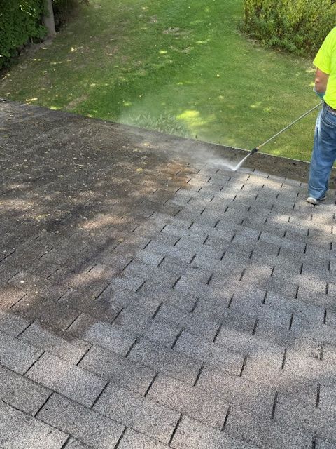 Person power washing a roof; half is cleaned, showing the contrast.