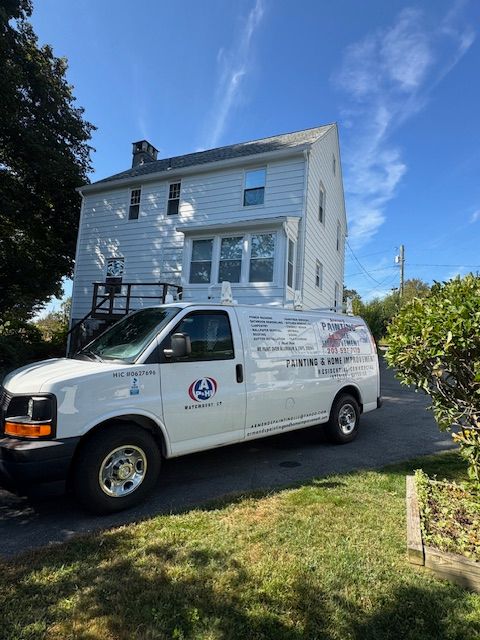 White van parked in front of a light-colored two-story house. Clear blue sky. Van has company logo.