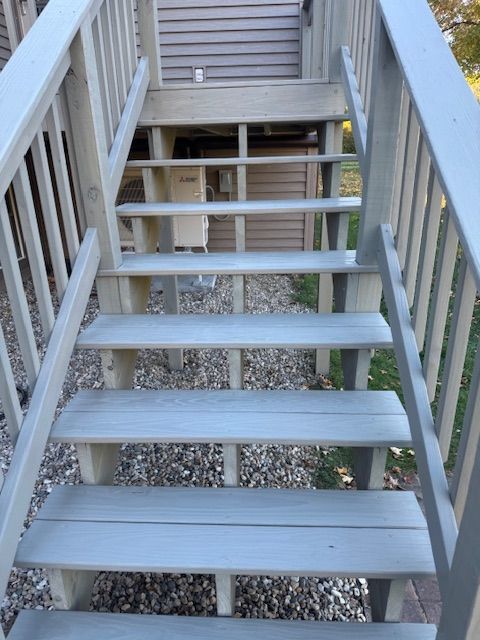 Wooden outdoor stairs painted light gray, leading up to a house.