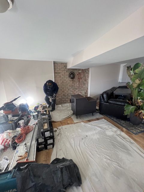 Person working in a room under renovation. Brick wall, tools, furniture covered in protective sheeting.