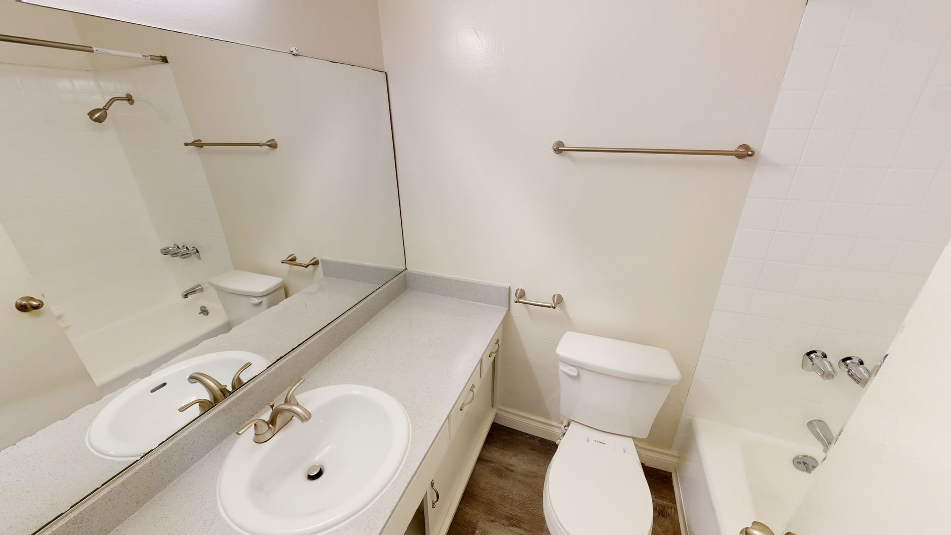 Bathroom with white walls, a sink, toilet, and bathtub. Beige counter and towel rack.
