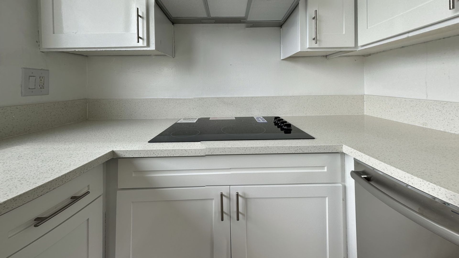 White kitchen cabinets and countertops with a black stovetop.