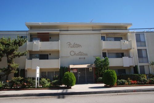 Fulton Chateau apartment building with white facade and sign on a sunny day.