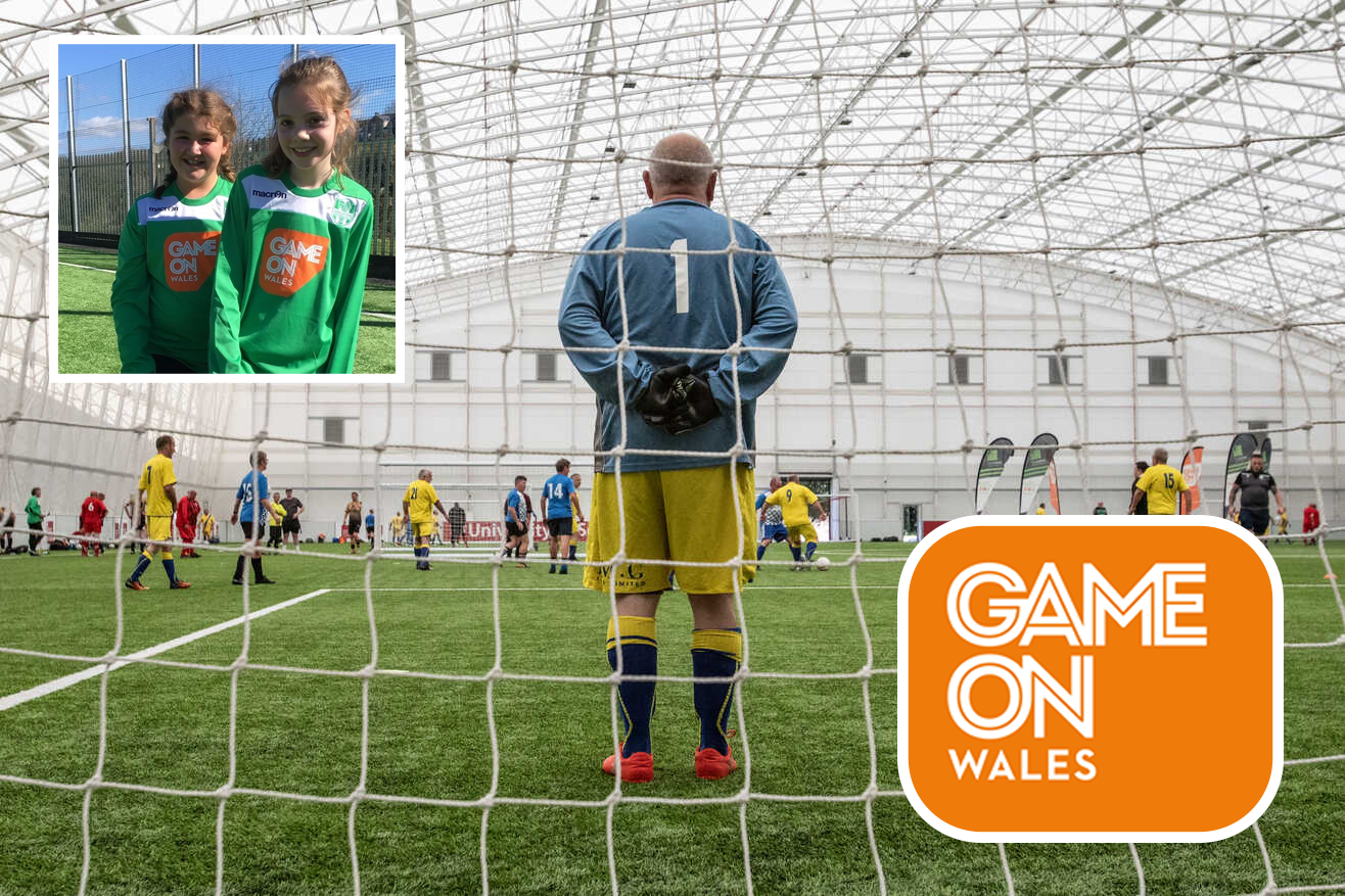 A man is standing in front of a soccer net watching a soccer game.