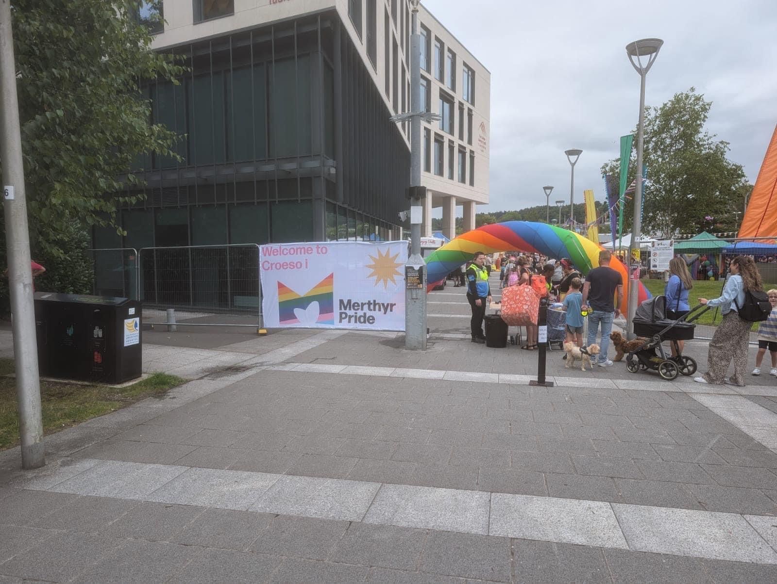 A group of people are standing in front of a building with a rainbow arch.