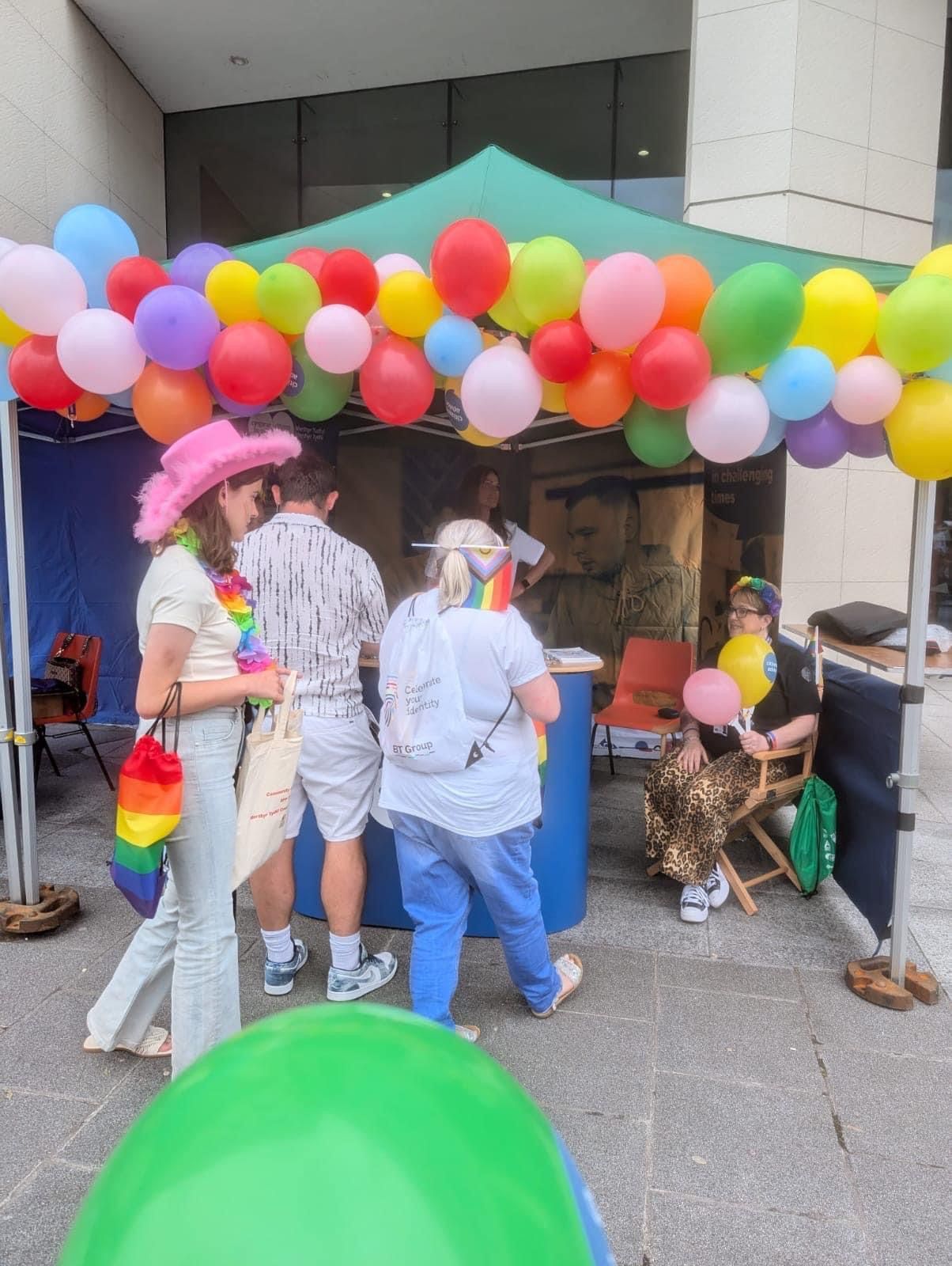 A group of people are standing in front of a tent covered in balloons.