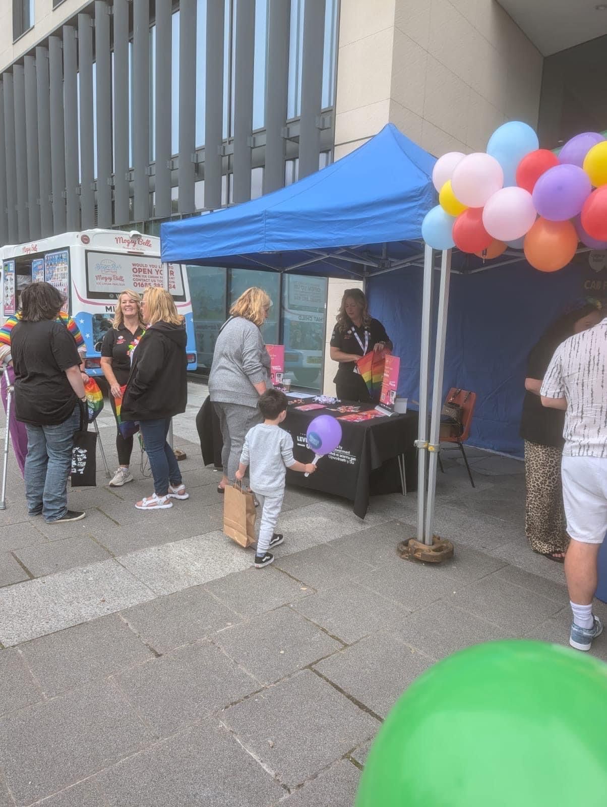 A group of people are standing around a table with balloons.