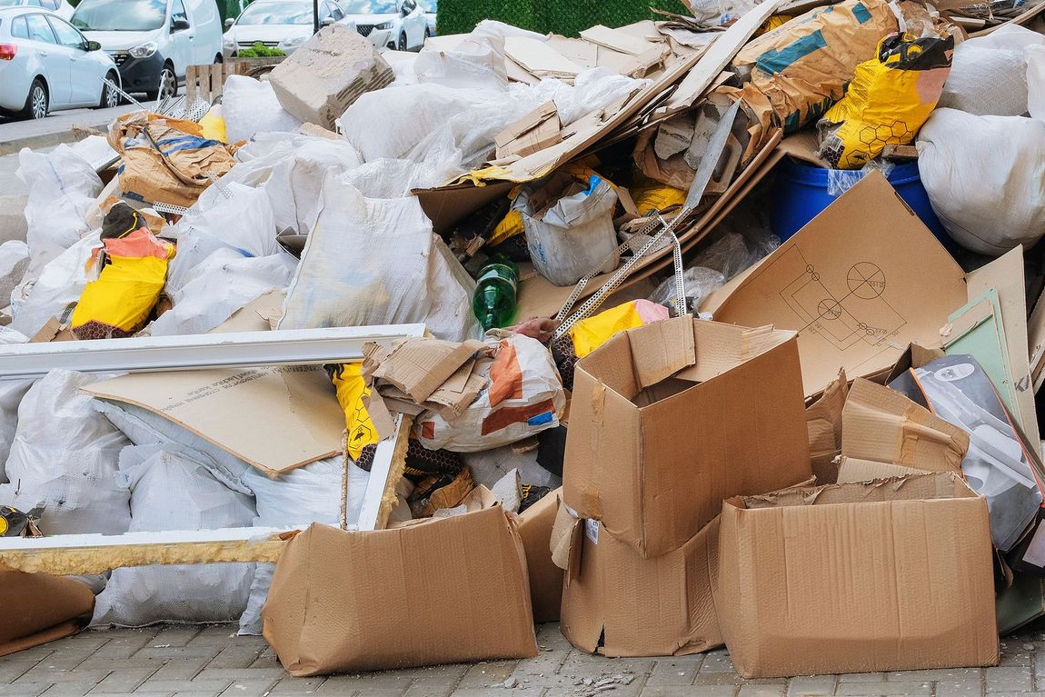 A pile of cardboard boxes and plastic bags on a sidewalk.