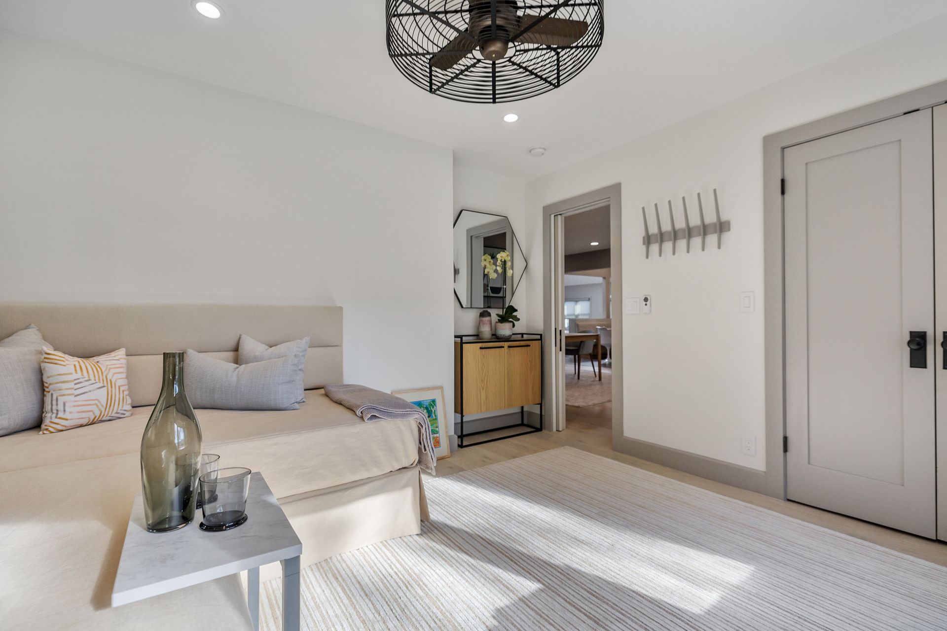 Bedroom with a daybed, side table, and a doorway to another room.
