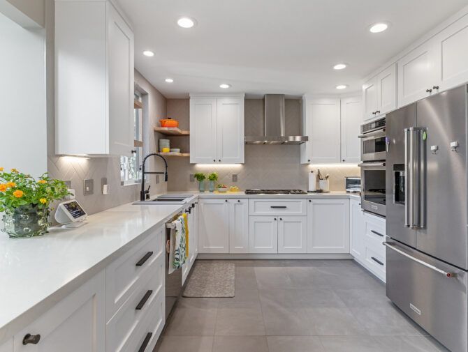 White kitchen with stainless steel appliances, white cabinets, and gray tiled floor.
