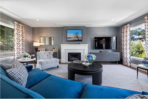 Living room with blue sofa, fireplace, TV, and patterned curtains.