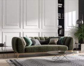 Green velvet sofa with pillows in a room with white panel walls, a coffee table, and a plant.