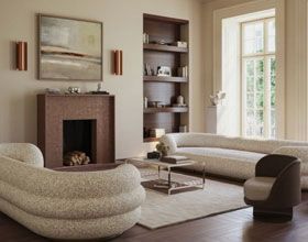 Living room with fireplace, bookshelves, light-colored sofas, and a window overlooking greenery.