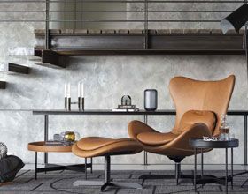 Leather chair and ottoman set in a modern living room, with side tables and shelves.