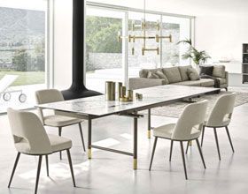 Modern dining room with marble table, cream chairs, and sofa. Natural light.