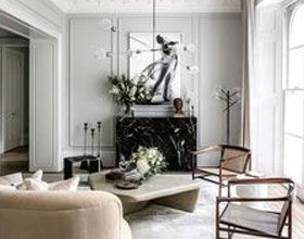 Elegant living room with neutral colors, black marble fireplace, artwork, and modern furniture.