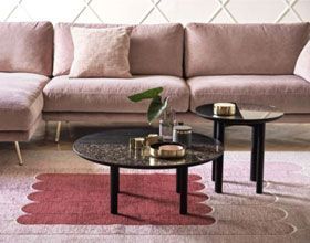 Pink sectional sofa with coffee tables on a patterned rug.