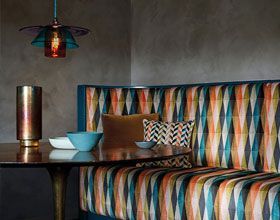 Dining nook with colorful patterned upholstery and a pendant light.
