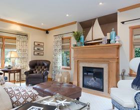 Living room with fireplace, nautical decor, brown leather armchair, and patterned curtains.