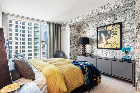 Bedroom with marble wallpaper, yellow and blue bedding, and a cityscape view.