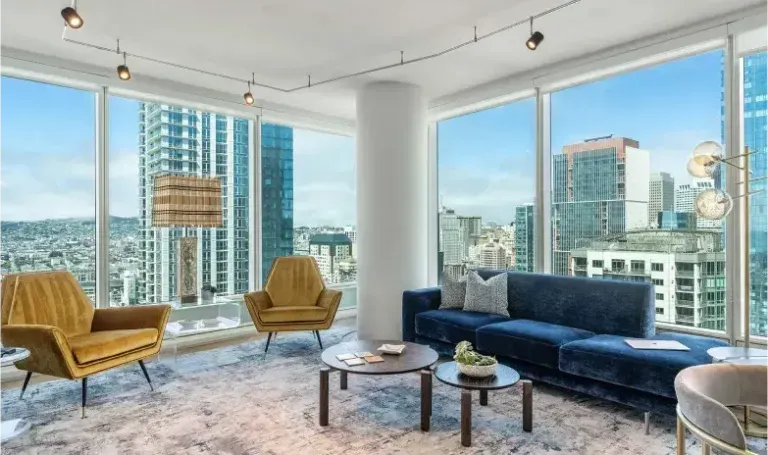 Living room with city view, blue couch, two yellow chairs, and modern lighting.