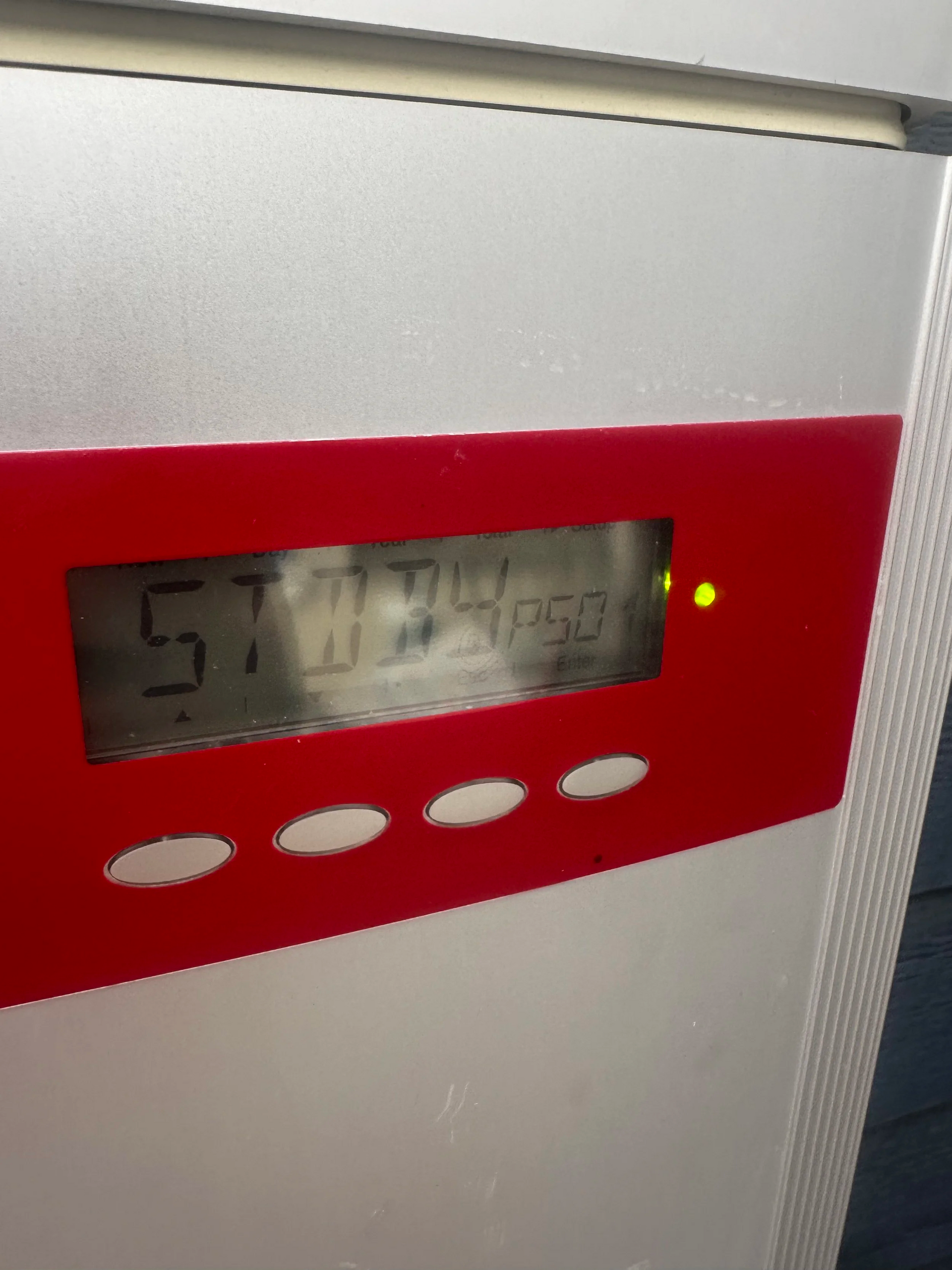 Close-up of a digital display on a red panel. Numbers 57 11 34 50 are shown with a yellow light.