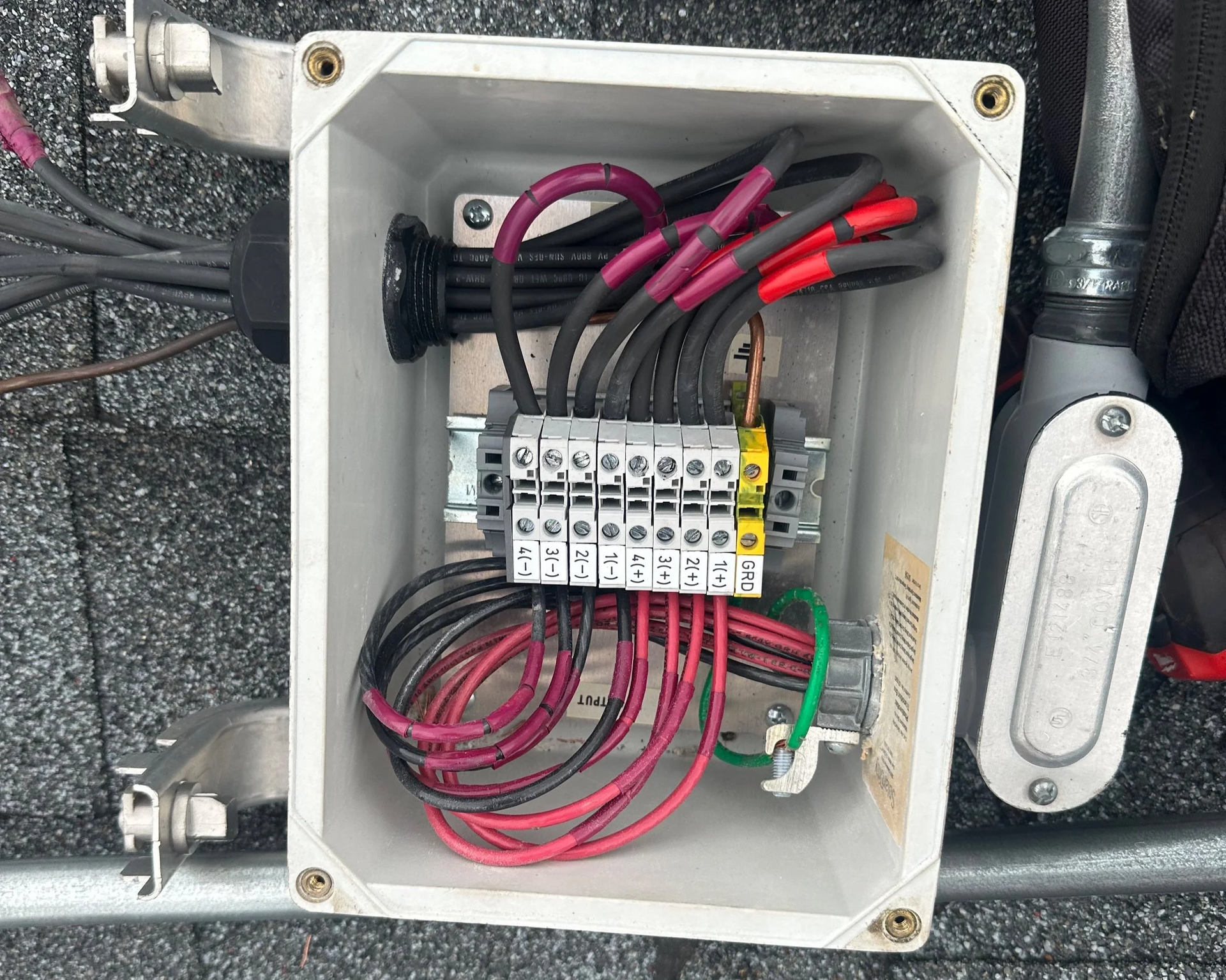 Open electrical junction box with wires connected to terminals. Black and red wires; green ground wire.