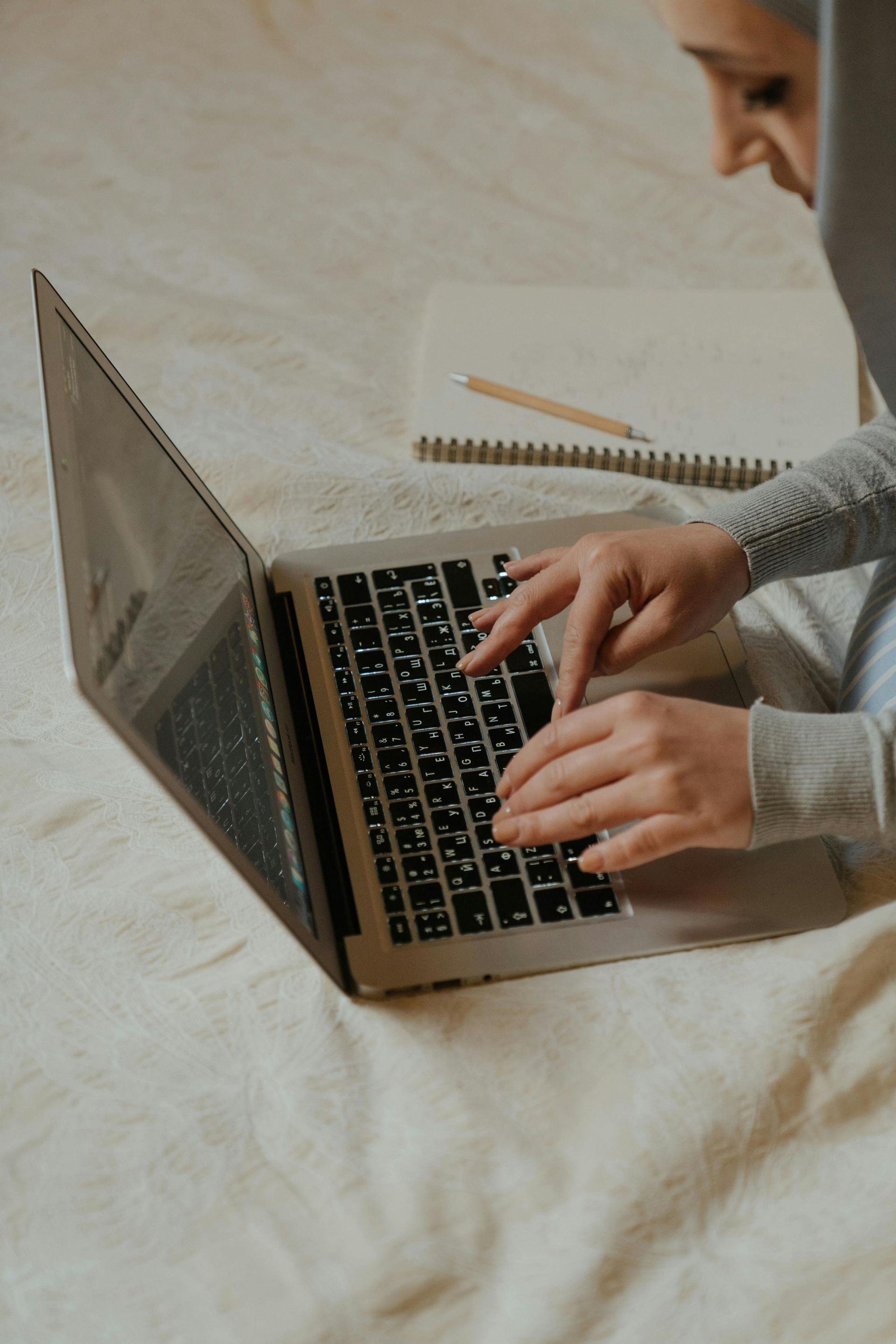 A woman is sitting on a bed using a laptop computer.