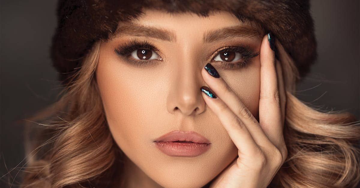 a woman wearing a fur hat covering her face with her hand