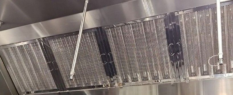 Cleaned stainless-steel grease filters installed in a commercial kitchen.