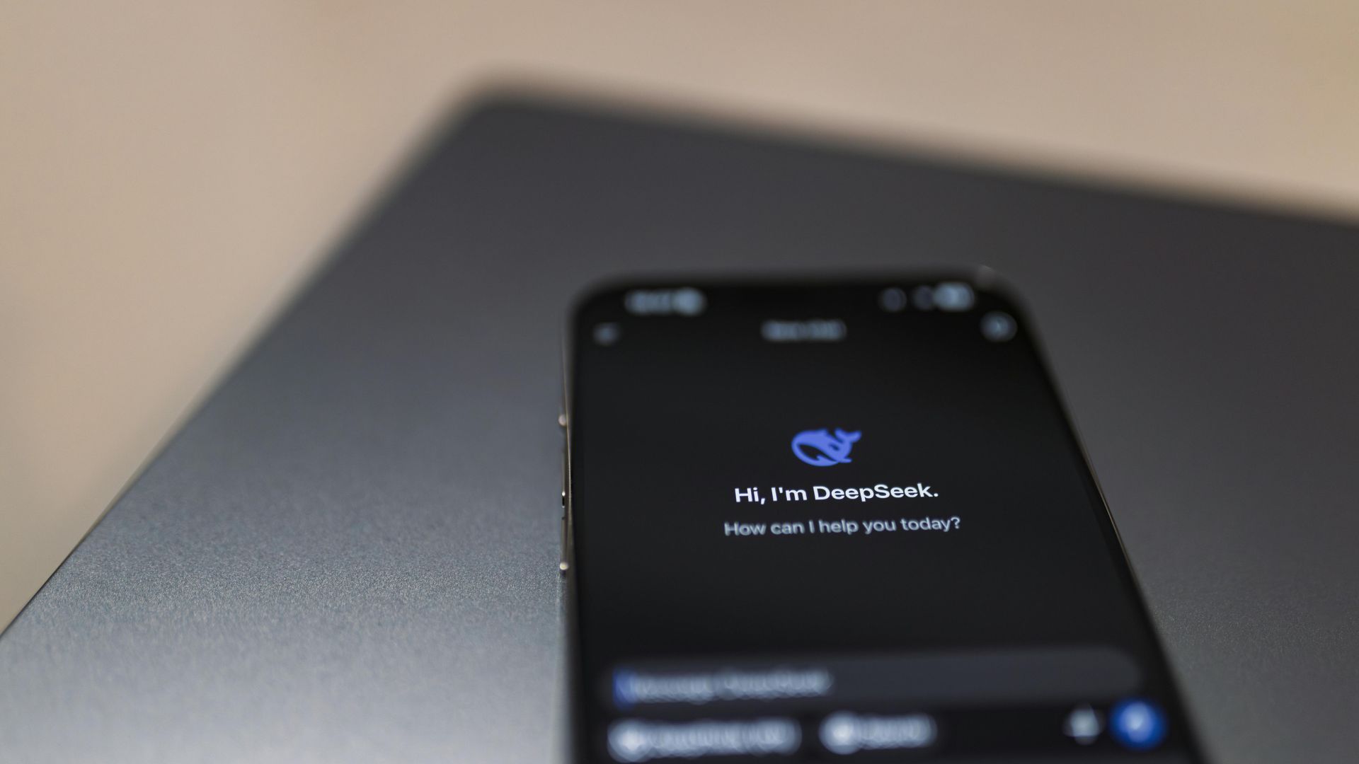 Écran de smartphone affichant une interface d'application sombre avec une icône de baleine bleue et du texte. Il est posé sur un ordinateur portable argenté.