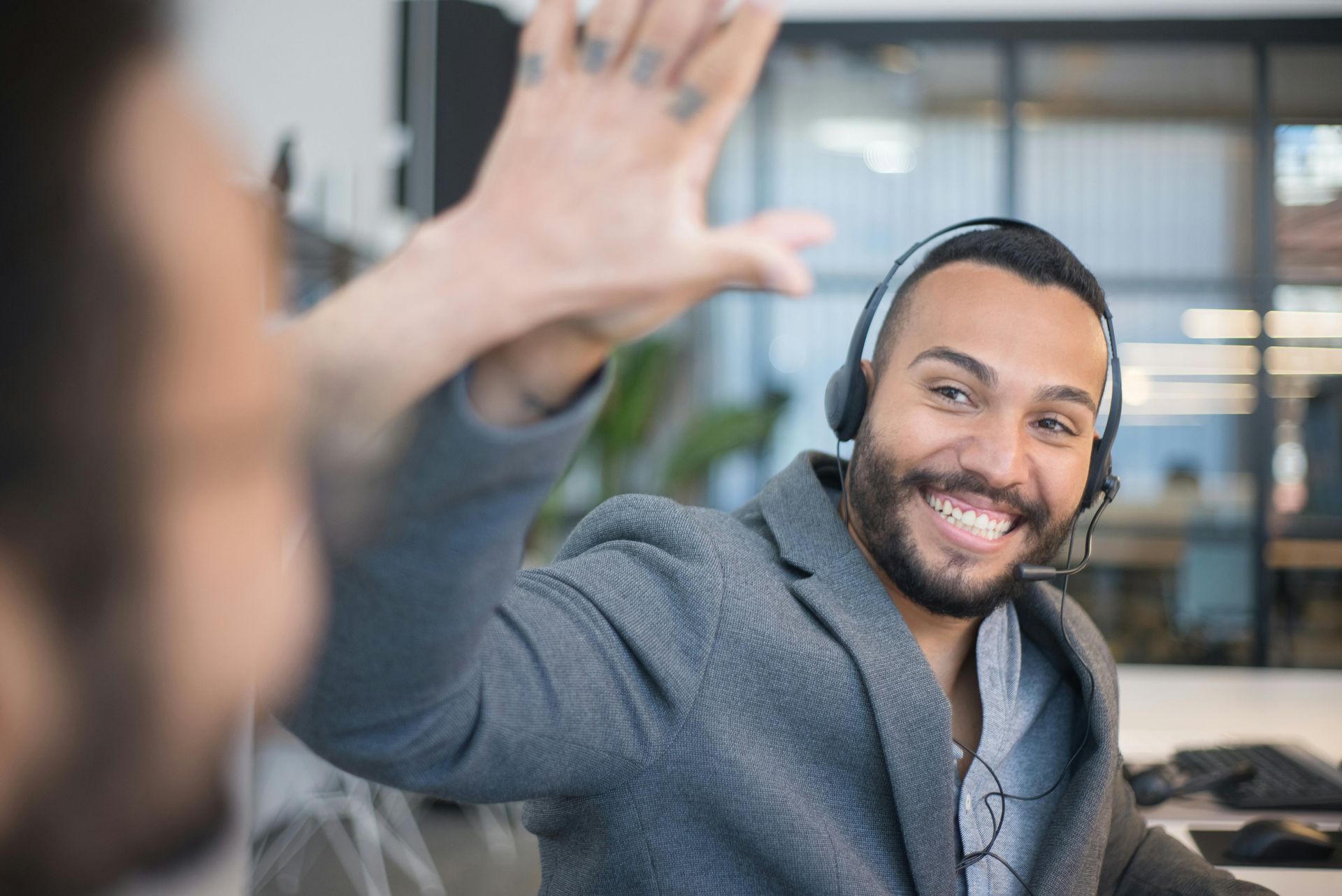 Un homme portant un casque audio sourit et tape dans la main de quelqu'un dans un bureau.