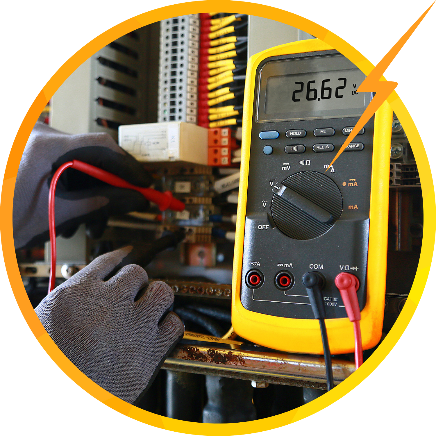 A person tests electrical components with a multimeter, wearing protective gloves, inside a control panel.