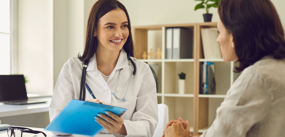 Doctor holding a blue folder while speaking with a patient in a bright office
