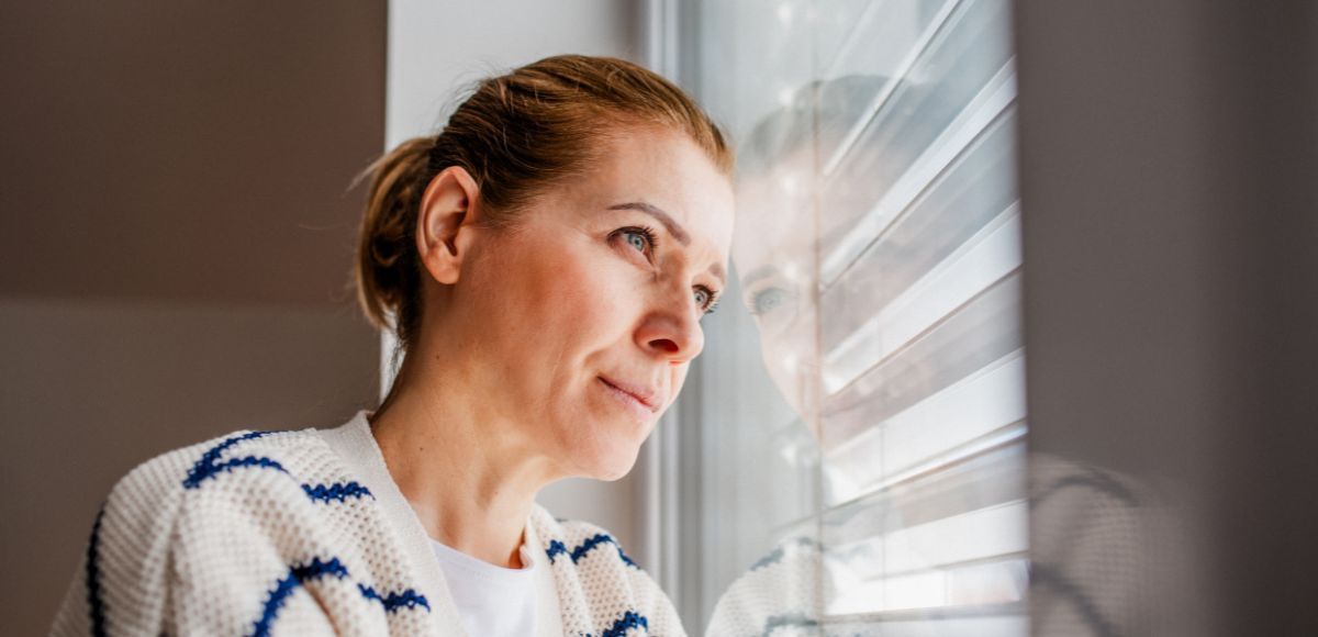 Perimenopause woman looking out the window stressed
