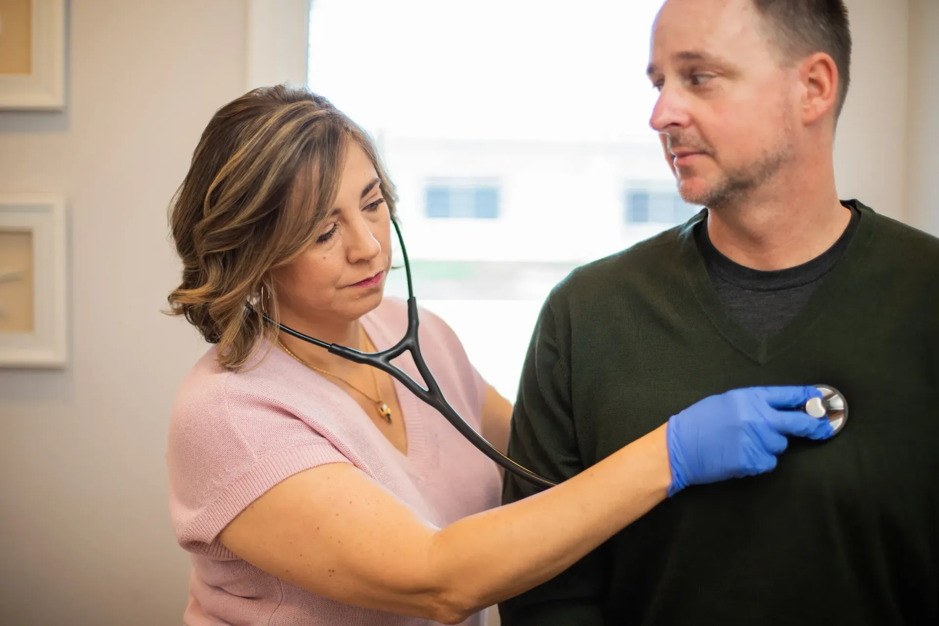 Care provider using a stethoscope to listen to the male patient’s chest during a general practice visit.