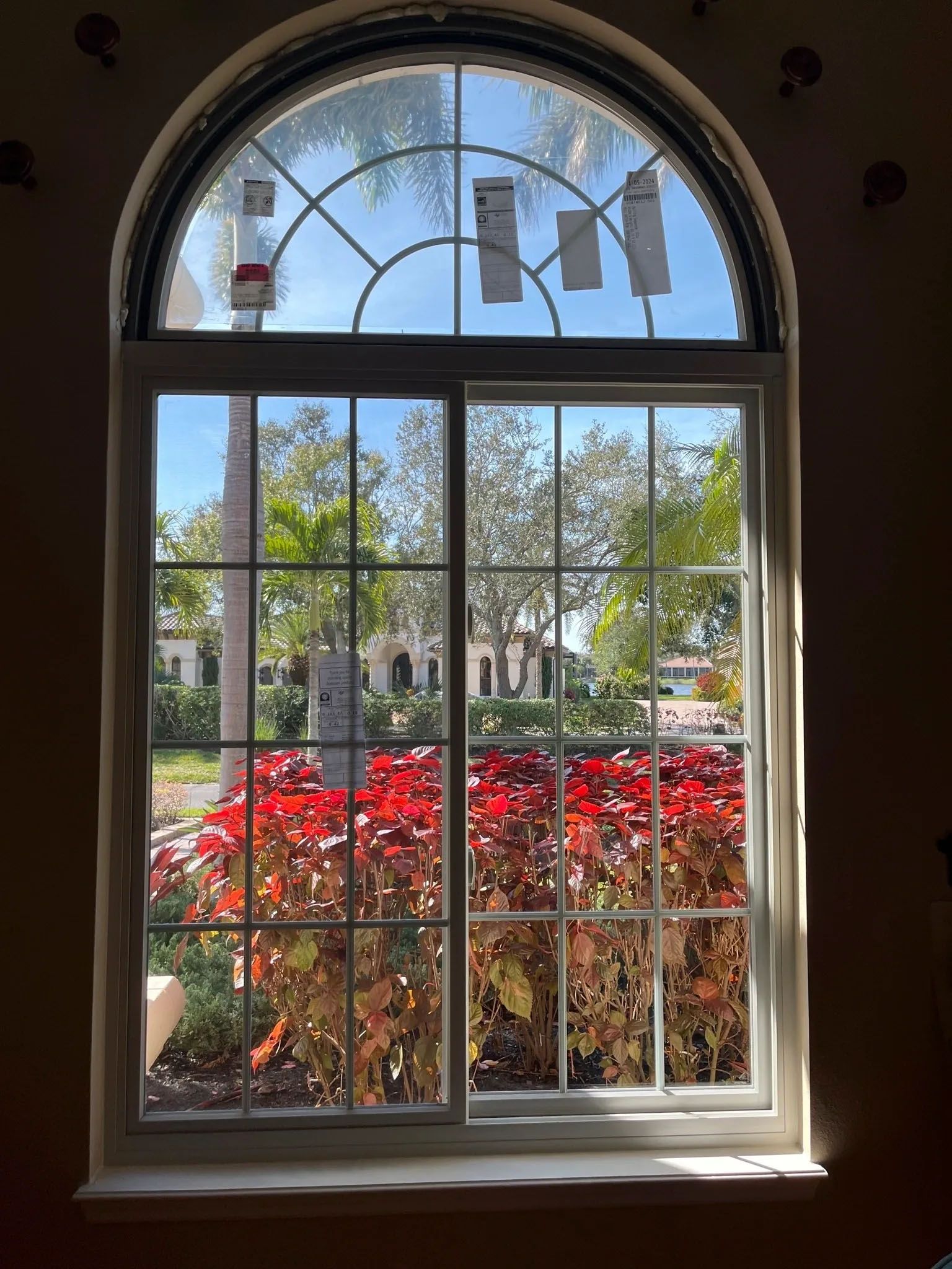 A large window with a stained glass design is looking out to a garden.