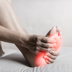 a person is holding their foot in pain with a red light shining on it .