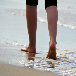 a person walking barefoot on a sandy beach with Leg Length Discrepancy