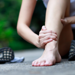 a woman is sitting on the ground holding her ankle in pain with a Personal Injury