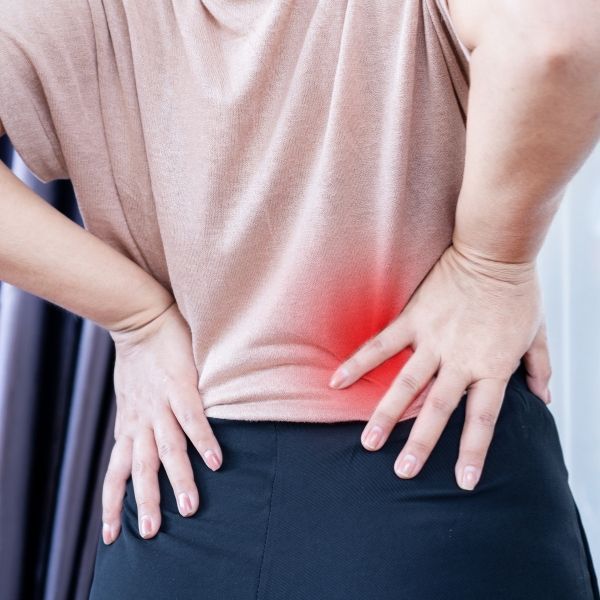 A woman is holding her back in pain due to sciatica