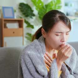 a woman is coughing while sitting on a couch .