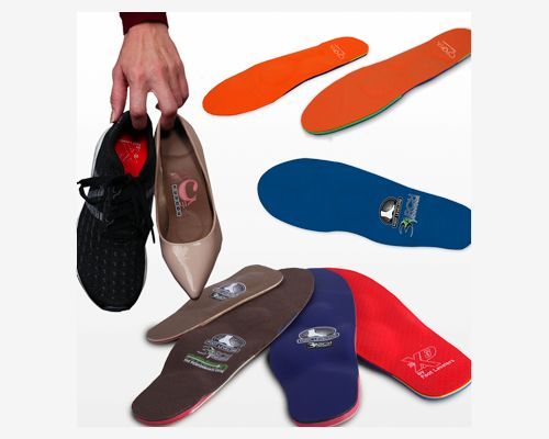 A person is holding a pair of shoes surrounded by custom orthotics