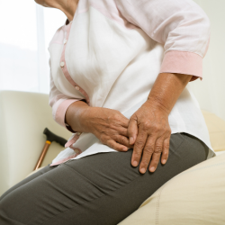 a woman is sitting on a couch with her hands on her hips, hip pain