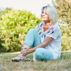 a woman is sitting on the grass with her legs crossed, Joint Sprains and Strains