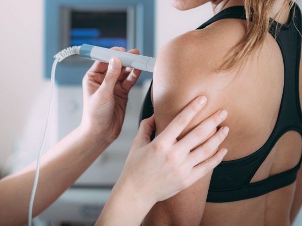 A woman is getting a laser therapy treatment on her shoulder.