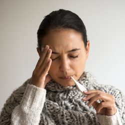 a woman in a sweater is holding a thermometer in her mouth, mild fever